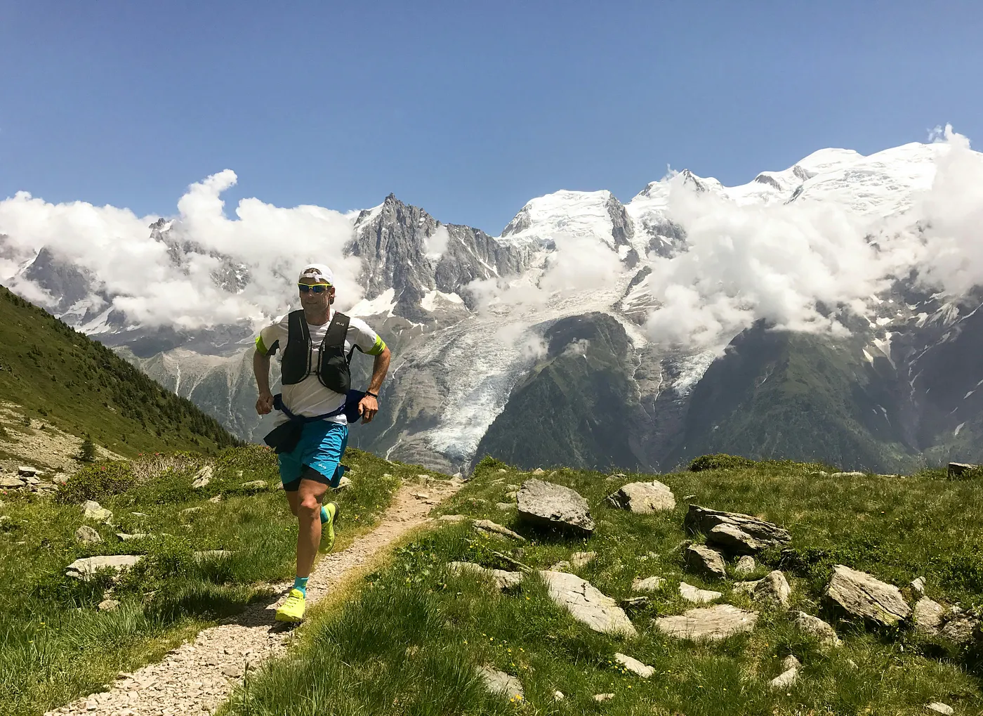 Trail runner descending a ridge above Chamonix, glaciers and clouds in the background